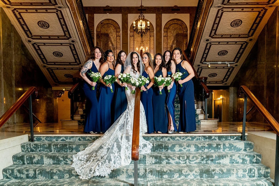Bridesmaids posing on the grand staircase at the Beacon Grand Hotel in San Francisco.
